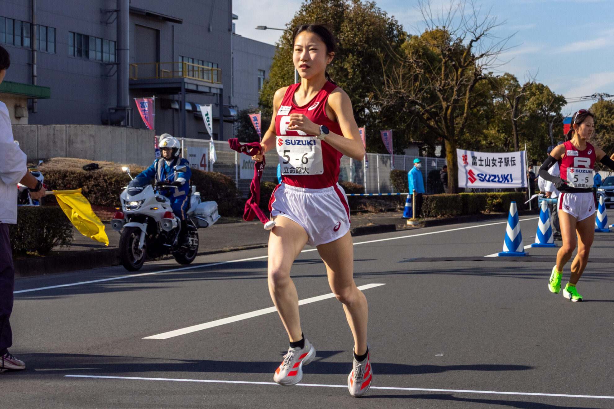 左手にたすきを持ち走る池田。隣の車線には白バイ。
