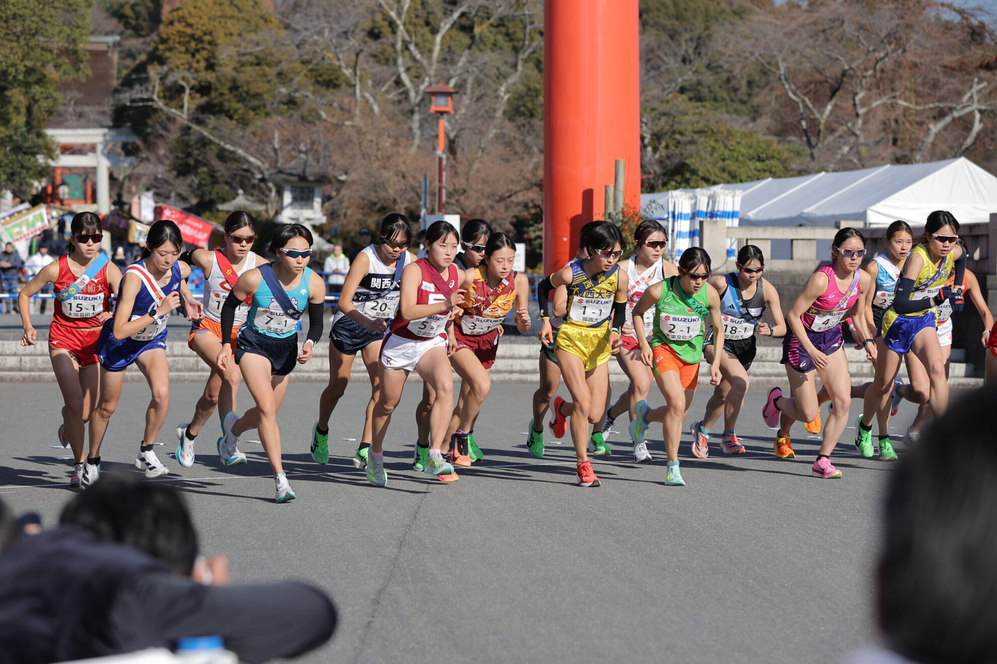一斉に走り出す選手ら。背景には鳥居。