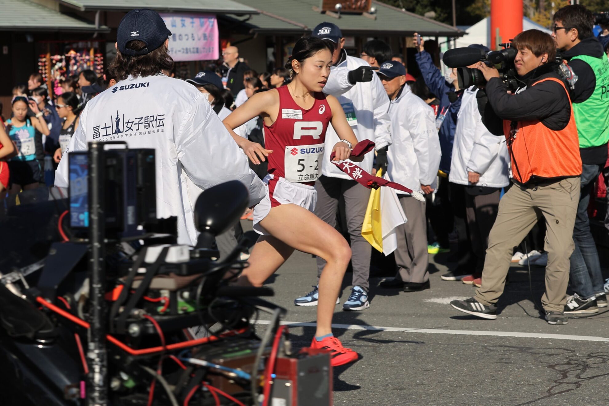 たすきを左手に持ち走る太田。後ろには多くのスタッフや報道関係者。